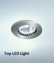The Premier Lite 12.105B Double Wide Display Counter, featuring a round, silver recessed LED light with a veneered wooden base, is illuminated against a plain light gray background. "Top LED Light" appears below the fixture.