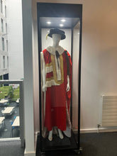 A Single Mannequin Showcase displays a mannequin in a ceremonial red and white robe with a fur collar and black hat inside a lockable cabinet within a modern building, with tables and chairs visible in the background.