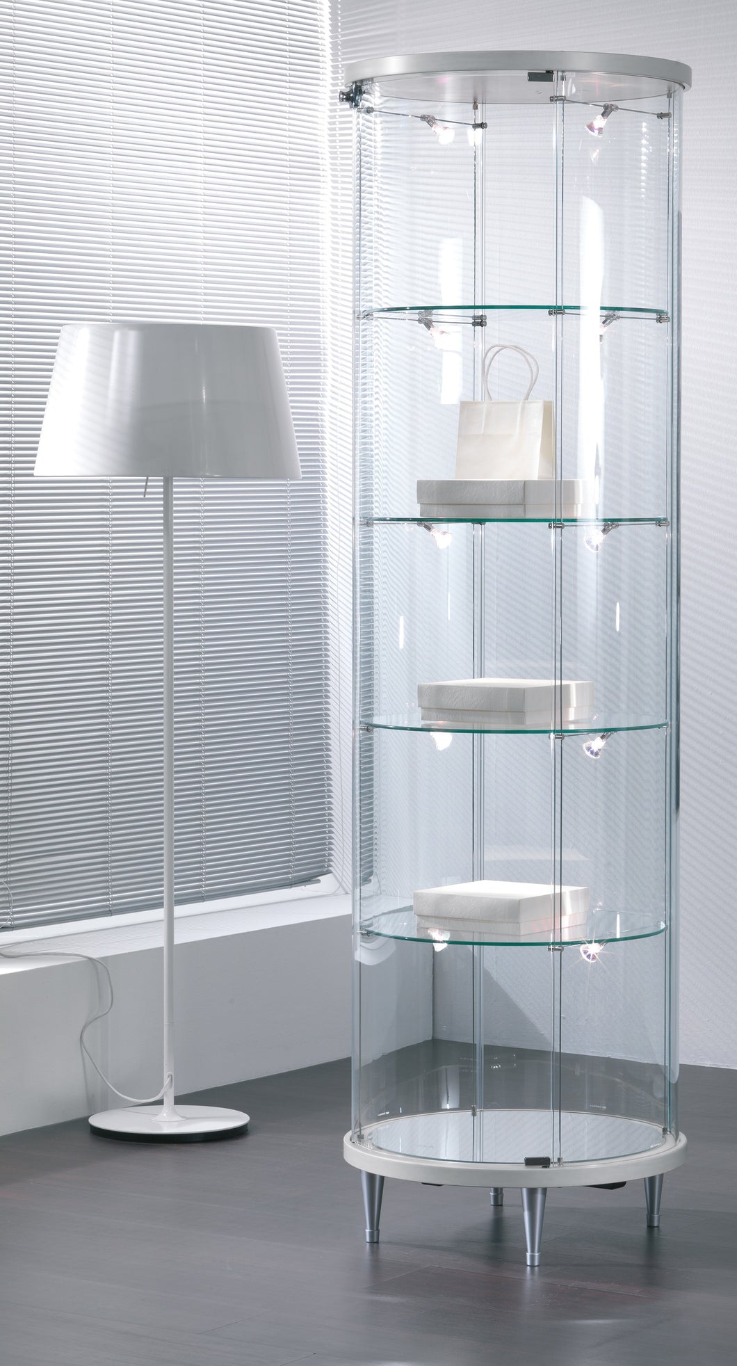 Elegant Elegance Lite 203/RF Round Display Showcase featuring a sleek glass design. This modern glass display cabinet is illuminated with LED lighting and showcases adjustable shelves, ideal for displaying collectibles or merchandise.