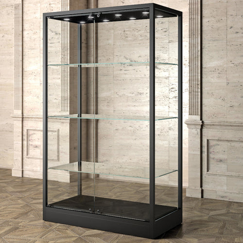 The Bravura MU120FC Display Showcase, featuring a black metal frame, tempered glass panels, and shelves, stands empty against a beige marble wall with decorative paneling and a patterned wooden floor.